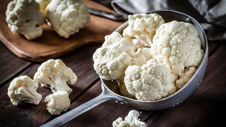 Fresh organic cauliflower in an old metal filter pot photographed on a rustic wooden table. This vegetable is considered a healthy salad topping. The main colors are white and brown. Low-key DSRL studio photo taken with Canon EOS 5D Mk II and Canon EF 100mm f/2.8L Macro IS USM